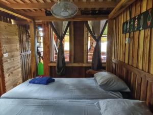 a bedroom with two beds in a wooden cabin at Barba Negra Adventure House in Sierpe