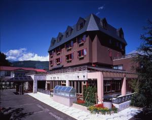 a large pink building with a black roof at Hakuba Hotel Ougiya in Hakuba