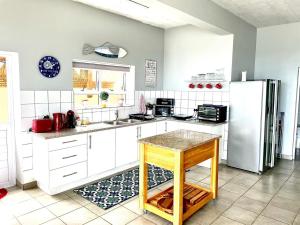 a kitchen with white cabinets and a refrigerator at the Boathouse in Jongensfontein