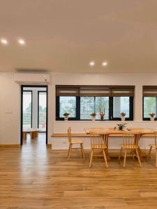 Làng HạにあるTAM ĐẢO GOLF VILLA 6 PHÒNG NGỦのテーブルと椅子と窓のあるダイニングルーム