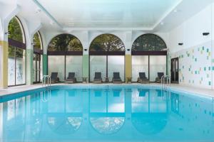 a swimming pool with chairs in a building with windows at London Marriott Hotel Regents Park in London