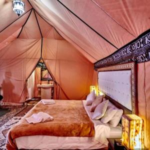 Desert Lover's Luxury Camp في مرزوقة: غرفة نوم بسرير في خيمة