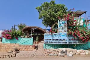 un panneau devant un bâtiment fleuri dans l'établissement Bedouin Garden Village, hotel Dive, à Aqaba