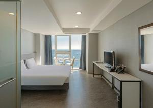 a hotel room with a bed and a desk with a television at Sun Cloud Hotel in Busan