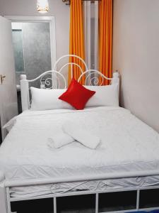a white bed with a red pillow on it at GCurtway Homes Tsavo Superior Studios in Nairobi