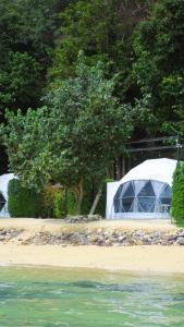 a tent and trees on a beach with water at Touch Glamping Koh Yao Noi ทัช แกรมปิ้ง เกาะยาวน้อย in Ko Yao Noi