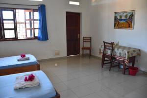 a room with two beds and a table and a chair at Centre Lucien Botovasoa in Diego Suarez