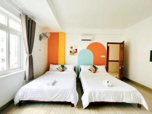 2 camas en una habitación con paredes de color naranja y blanco en Hệ thống Myla - Trụ sở Ks Kim Liên, en Vung Tau