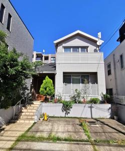 a large white house with a driveway in front of it at Bell house in Tokyo