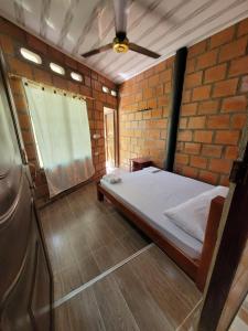a small room with a bed in a brick wall at Estadero y Hospedaje las Pavas in Norcasia