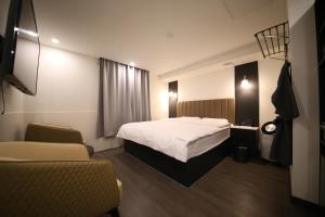 Uiwangにある25 Hotelのベッド1台と椅子2脚が備わるホテルルームです。