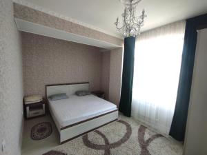 een slaapkamer met een bed met een kroonluchter en een raam bij Prestigious apartment in Bishkek in Bisjkek