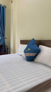 a bed with a blue pillow on top of it at Nhà Nghỉ Hương Trà Minh Đài 