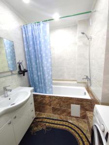 een badkamer met een bad, een wastafel en een douche bij Prestigious apartment in Bishkek in Bisjkek