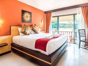 a bedroom with a large bed with an orange wall at Chiangkhong Teak Garden Riverfront Onsen Hotel- SHA Extra Plus in Chiang Khong