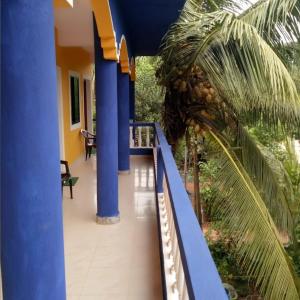 un balcon d'une maison avec des colonnes bleues et un palmier dans l'établissement PARVATI MANDREM, à Mandrem