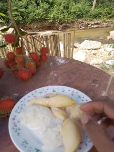 a person holding a plate with a banana on it at Dango1881muslim riverstay in Padang Rengas