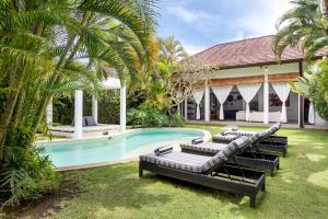 a pool with lounge chairs and a house at Villa Alice in Seminyak