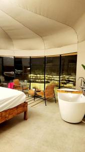 a bedroom with a tub and a bed and a balcony at Starry Domes Desert Camp in Badīyah