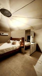 een grote kamer met 2 bedden en een plafond bij Starry Domes Desert Camp in Badīyah