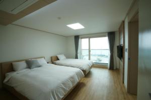 um quarto de hotel com duas camas e uma janela em The Beach Pension em Jeju
