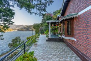 a brick building next to a body of water at SaffronStays Gardens On The Lake, Bhimtal - pet-friendly garden villa by the lake in Bhīm Tāl