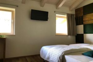 a bedroom with two beds and a television on the wall at B&B Le Stagioni di Stava in Tesero