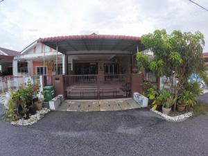 een huis met een poort en een veranda met planten bij D HOMESTAY SERI ISKANDAR in Seri Iskandar