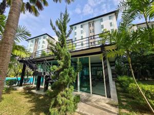 a house with a balcony and palm trees at Le Breeze Resort Hua hin in Cha Am