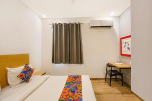 a hotel room with a bed and a desk and a window at FabHotel Roseman in New Delhi