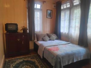 1 dormitorio con 2 camas, TV y ventanas en Darjeeling BnB, en Darjeeling