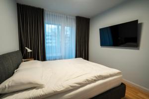 een slaapkamer met een bed en een flatscreen-tv bij Sunrise Ugales Apartments in Liepāja
