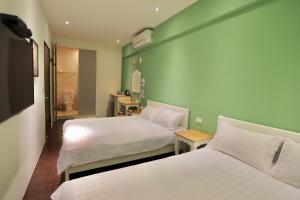 2 Betten in einem Zimmer mit grünen Wänden in der Unterkunft 好窩旅店 in Altstadt von Hengchun