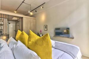 ein Schlafzimmer mit weißen und gelben Kissen auf einem Bett in der Unterkunft Luxury urban living at The Harri in Kapstadt