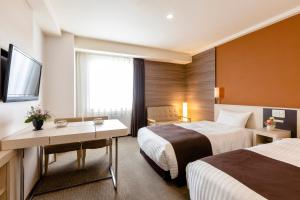 銚子市にある銚子プラザホテルのベッド2台とテレビが備わるホテルルームです。