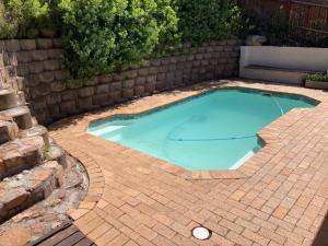 a small swimming pool on a brick patio at Two Oceans Artist's Home. in Fish Hoek