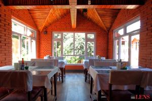 a dining room with tables and chairs and windows at Melungtse apartment in Kathmandu