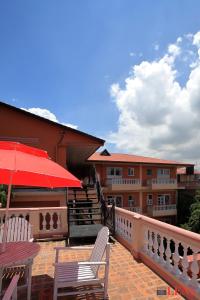 a patio with two chairs and a red umbrella at Melungtse apartment in Kathmandu