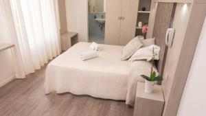 a small bedroom with a white bed and a mirror at Design Hotel Astra B&B in Misano Adriatico