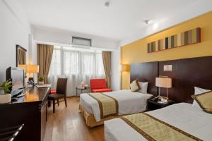 a hotel room with two beds and a desk at Bao Son International Hotel in Hanoi