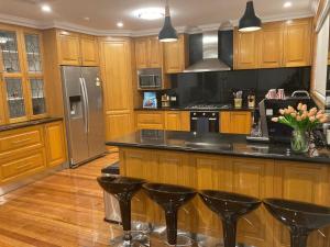 una cocina con armarios de madera y encimeras negras en Style/Comfort/Spacious 4 bedroom house plus study, en Melbourne