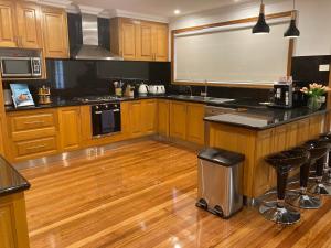 una cocina con armarios de madera y encimeras negras en Style/Comfort/Spacious 4 bedroom house plus study, en Melbourne
