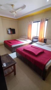 una camera con 2 letti, un tavolo e una TV di Hotel Vithai Niwas a Shirdi