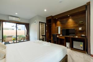 a bedroom with a large white bed and a flat screen tv at บีวินรีสอร์ท in Nakhon Si Thammarat