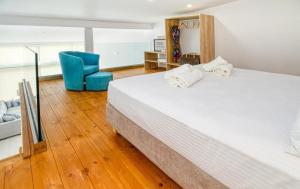 1 dormitorio con 1 cama grande y 1 silla azul en Cocoon Luxury Villas, en Máleme