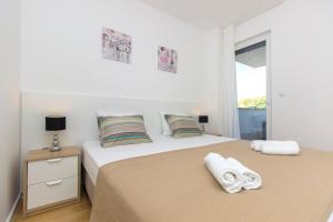 ein weißes Schlafzimmer mit einem großen Bett mit Handtüchern darauf in der Unterkunft Royal Primošten in Primošten