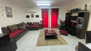 Your Home in Madinaty في Madīnat ash Shurūq: غرفة معيشة مع أريكة وتلفزيون