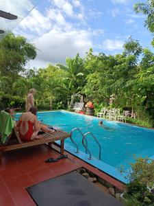 a man sitting on a bench next to a swimming pool at Hugo Homestay in Phong Nha