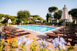 a swimming pool with lounge chairs and umbrellas at Villa Acquaviva Wine Resort in Montemerano