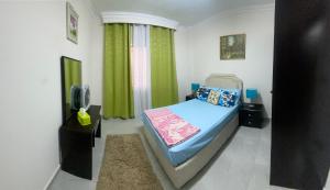 Your Home in Madinaty في Madīnat ash Shurūq: غرفة نوم صغيرة بها سرير وتلفزيون